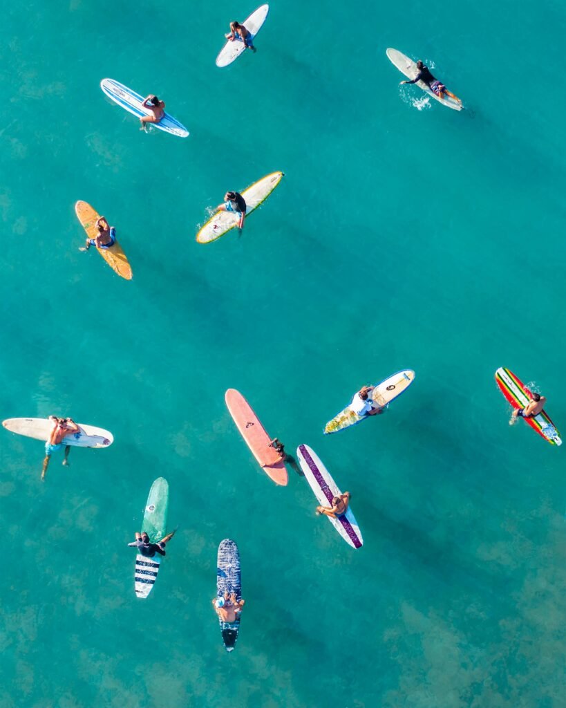 A vibrant aerial shot of surfers on colorful boards in turquoise waters, capturing Hawaiian surfing culture.