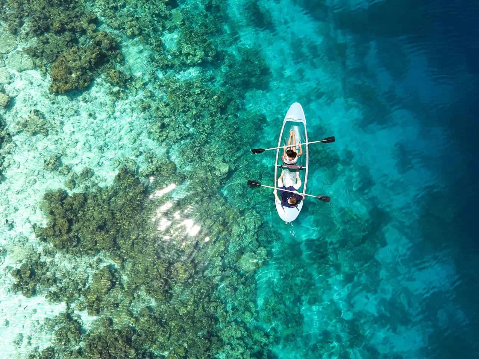 Aerial view of clear canoe gliding over vibrant coral reefs in Great Barrier Reef's turquoise waters.One of Natural Wonders