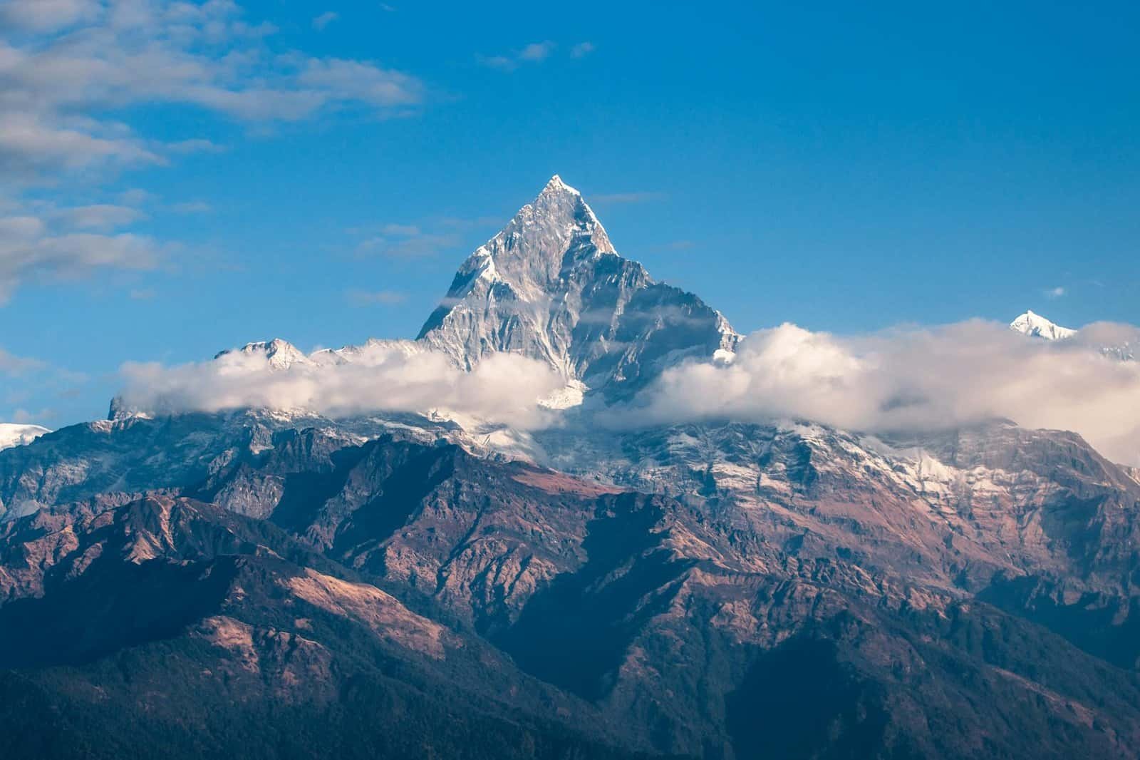 Breathtaking view of a snow-covered Mount Everest surrounded by clouds during sunrise. Natural Wonders